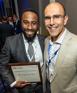Picture of an award winner holding a plaque with a colleague.